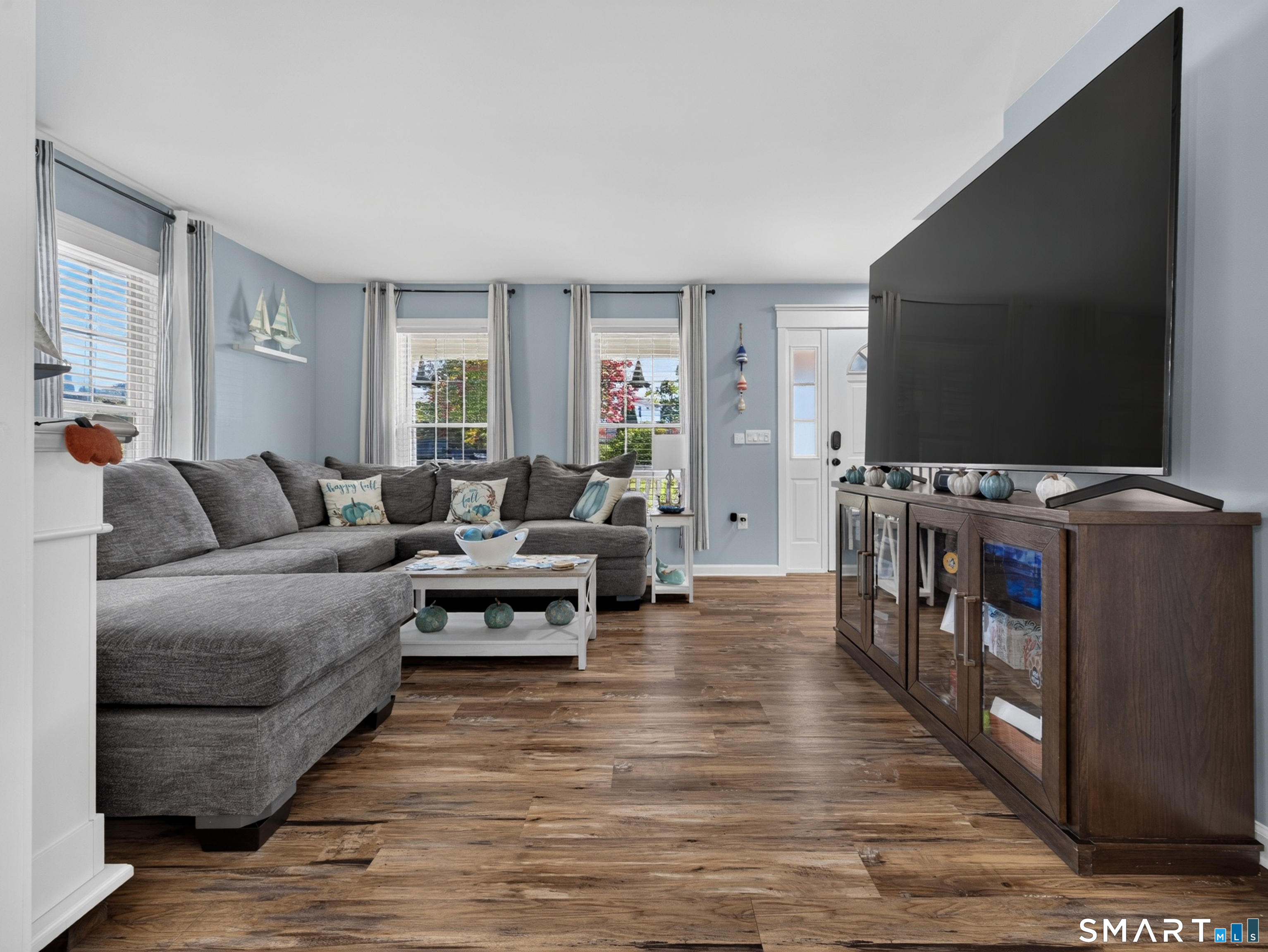 Living room with a gray sectional, wood floors, and a large television.
