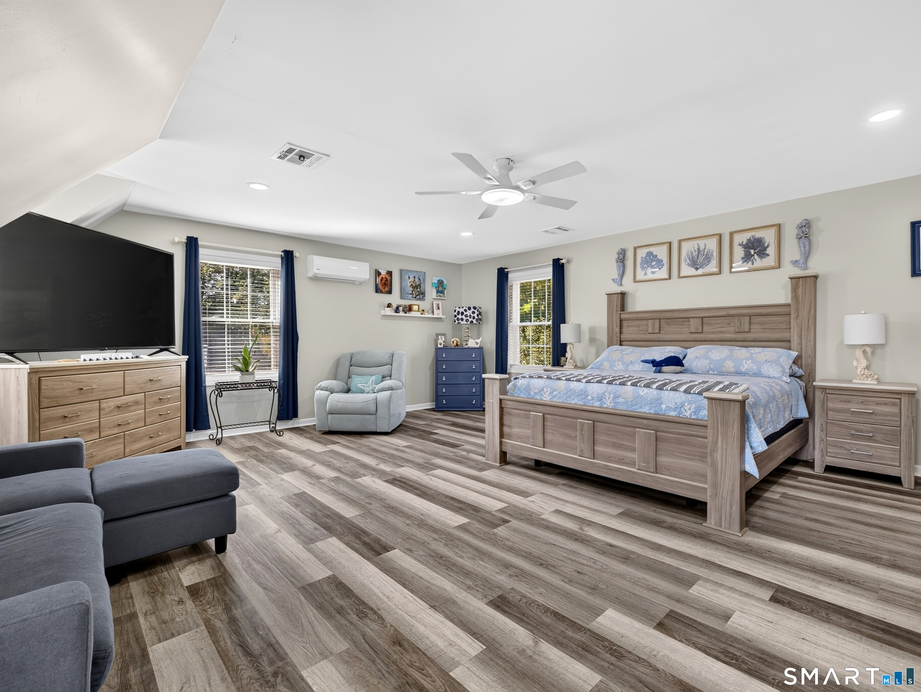 Furnished bedroom with a large wood bed, blue bedding, and plank flooring.