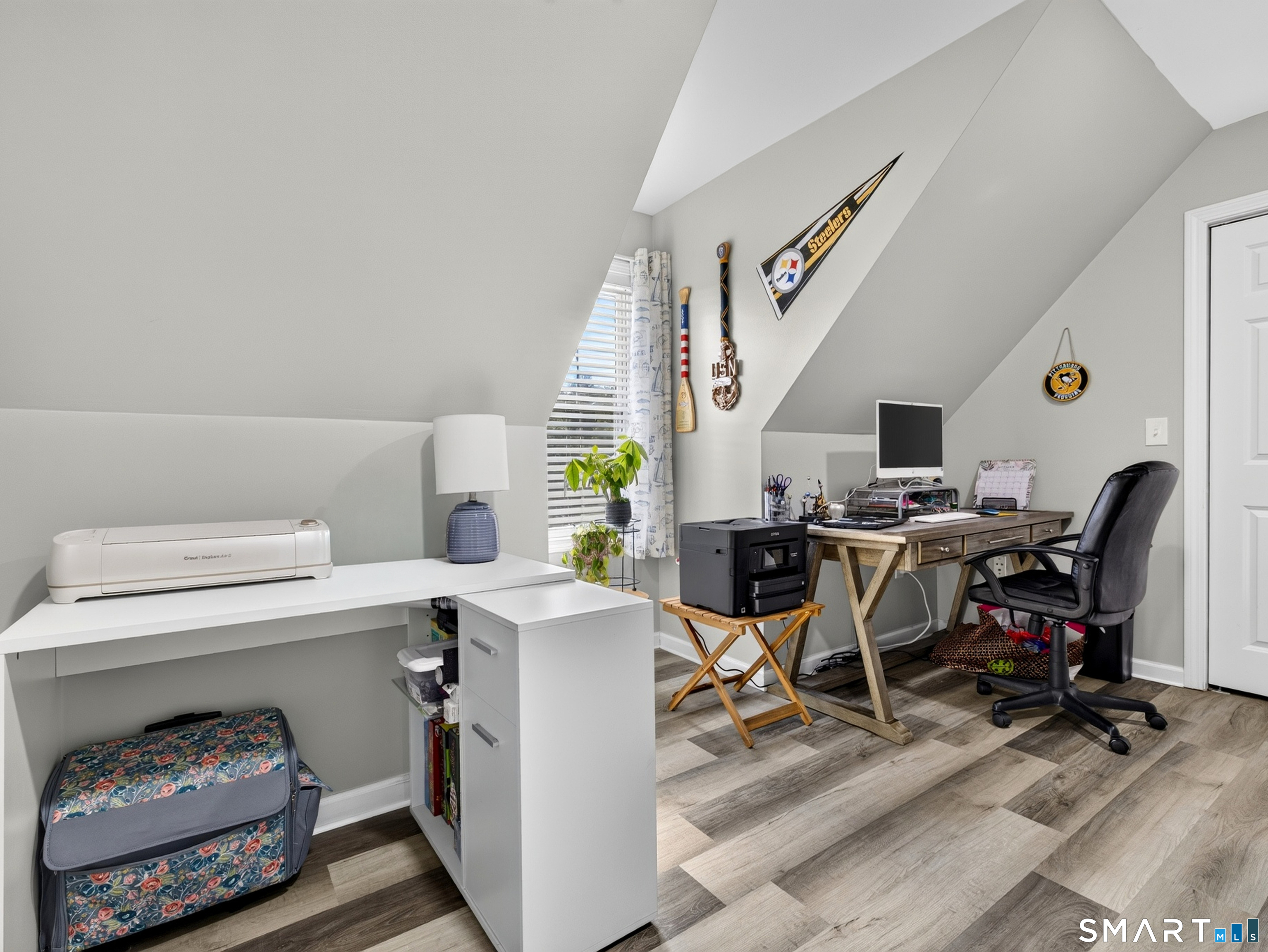 Loft home office with a wooden desk, black office chair, and Steelers pennant.