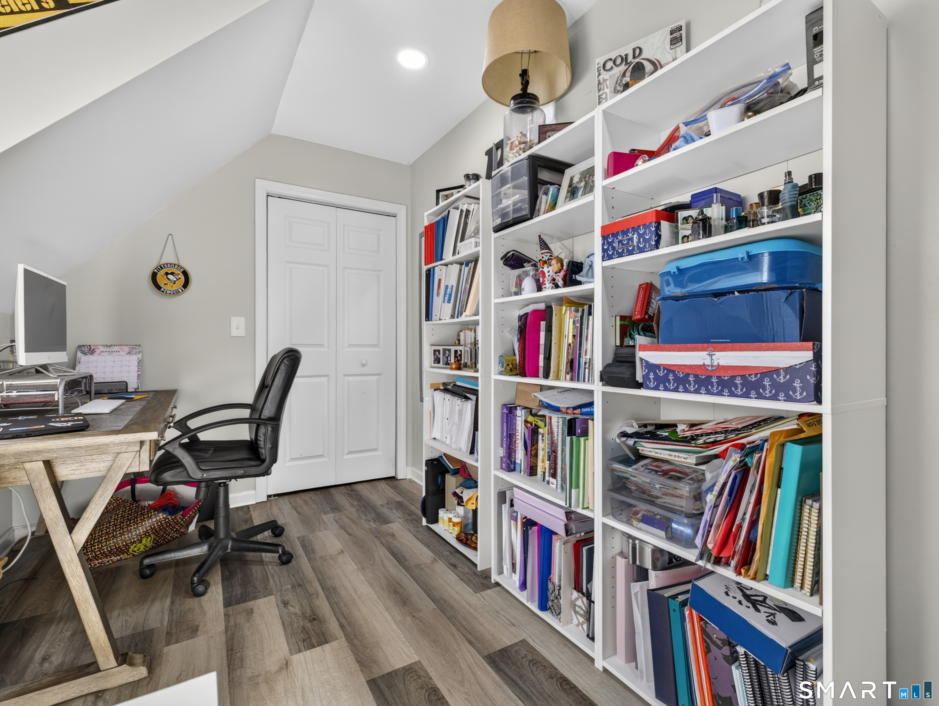 Home office with extensive white shelving, a desk, and a black office chair.