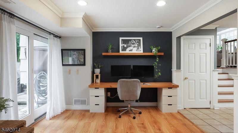 Home office with a long wood desk against a dark accent wall and sliding doors to a patio.