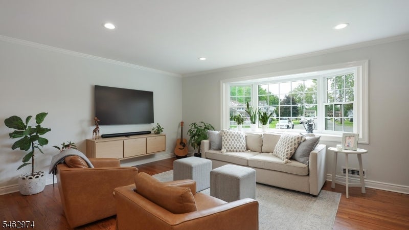 Living room with a cream sofa facing caramel leather armchairs beside a large bay window.