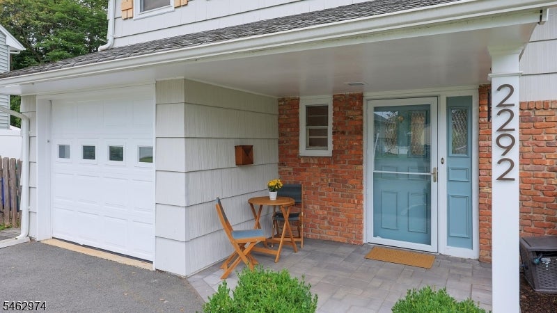 House entrance with a blue door, brick facade, attached garage, and covered porch.