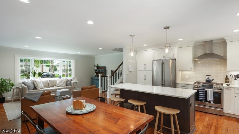 Open-plan kitchen and dining area with a large island, stainless steel appliances, and hardwood floors.