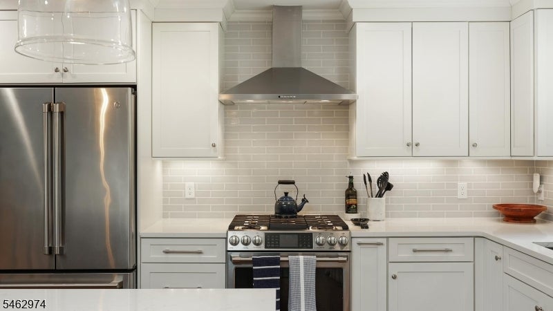 Kitchen with white cabinets, gray tile backsplash, and stainless-steel appliances.