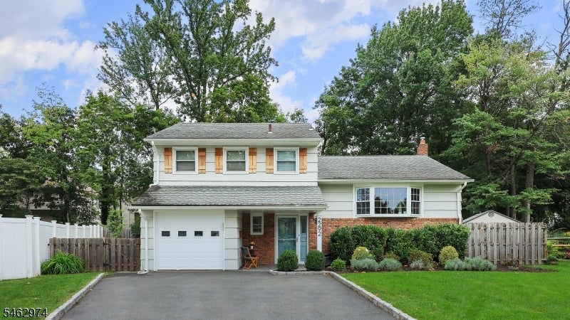 Two-story white home with brick accents, an attached garage, and a wide paved driveway.