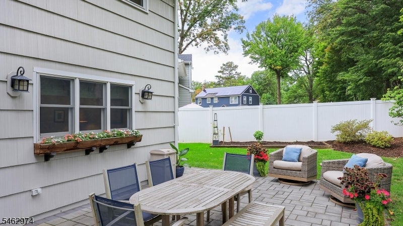 Backyard patio with a paver dining area, lounge chairs, and white privacy fence.