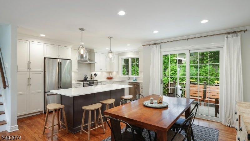 Kitchen and dining area with a white-topped island, wooden table, and sliding doors to a deck.