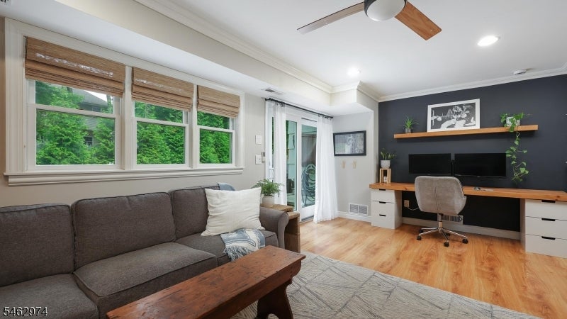 Living room and home office with a gray sofa, large windows, and built-in desk.