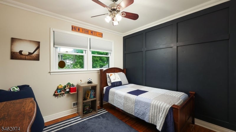 Bedroom with blue-and-white bedding, a dark paneled accent wall, and a New York Mets sign.