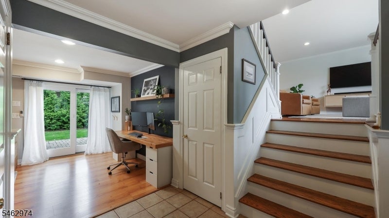 Entry foyer with wood-tread staircase and a desk nook beside glass doors to the garden.