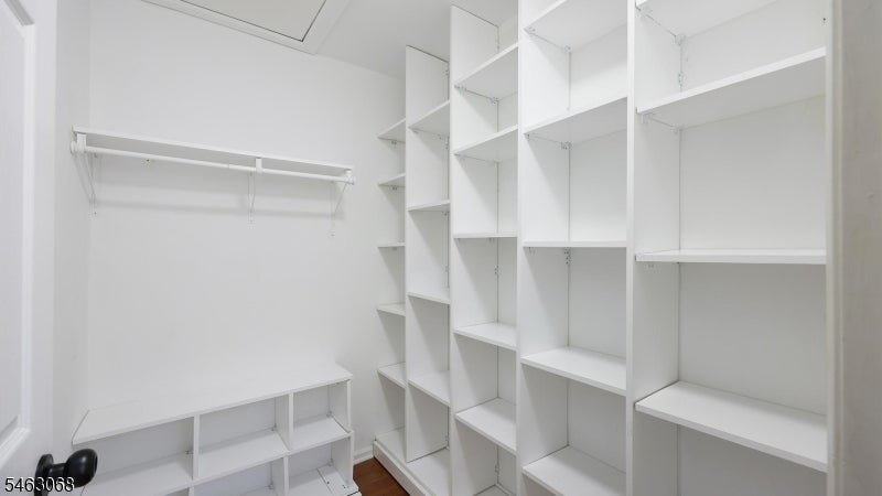 Walk-in closet with extensive white built-in shelving, lower cubbies, and a hanging rod.