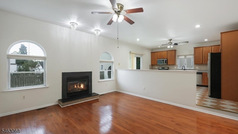 Living room with hardwood floors, a lit fireplace, and an open kitchen.