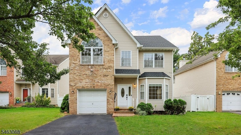 Two-story brick-and-siding house with a single-car garage and mature trees framing the front lawn.