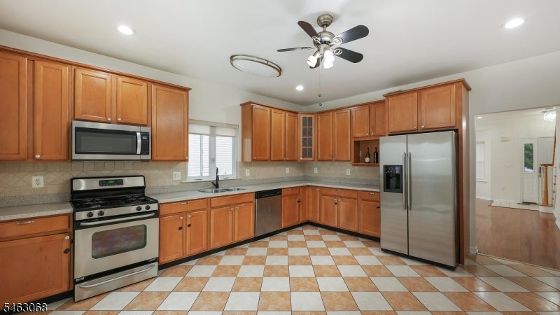 Kitchen with wood cabinets, stainless steel appliances, and a checkerboard tile floor.