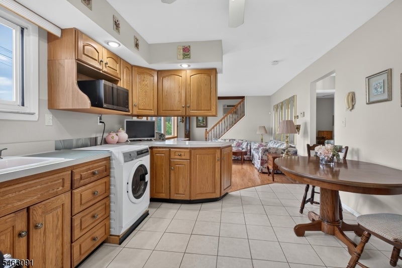 Kitchen with warm wood cabinetry, a peninsula, and a front-loading washer beside the dining area.