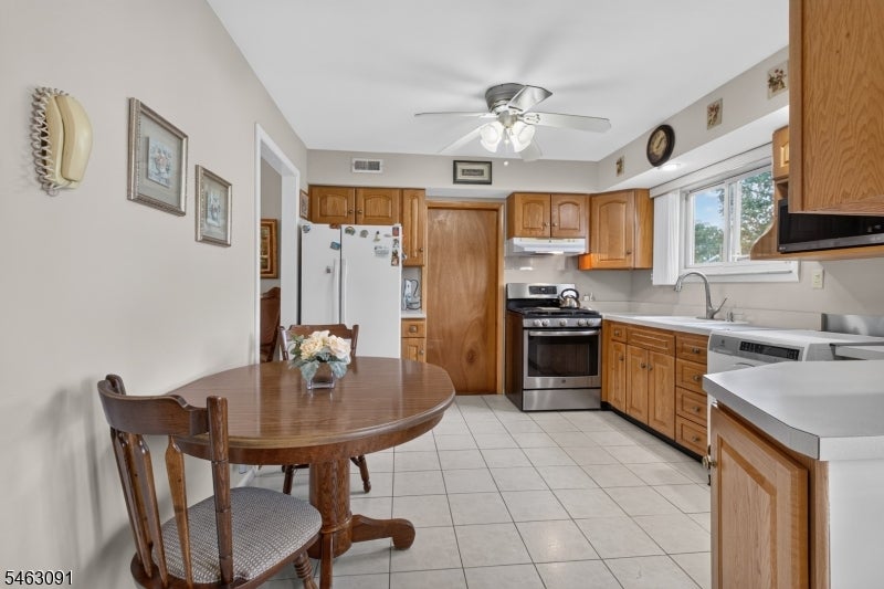 Kitchen with wood cabinets, stainless steel appliances, and a round dining table beside the window.