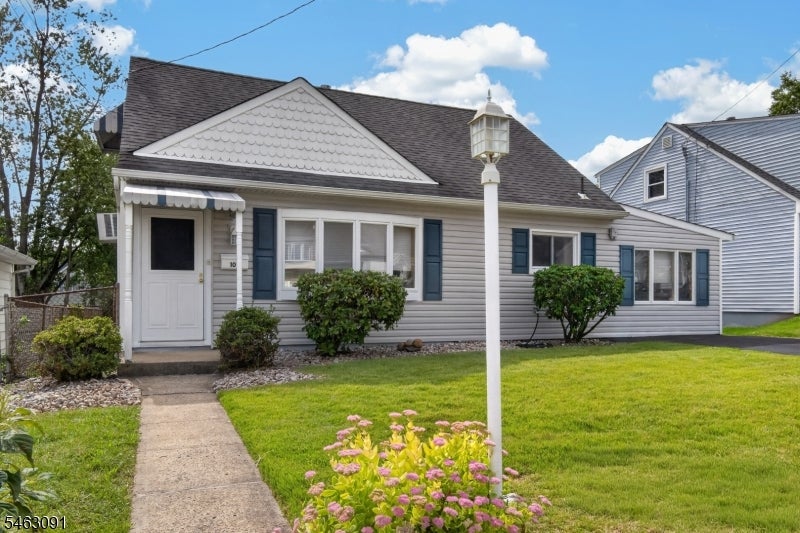 Single-story gray-sided home with dark shutters, front walkway, lawn, and white lamp post.
