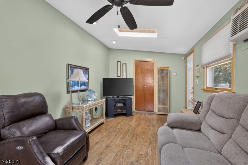 Living room with pale green walls, wood flooring, two sofas, and a ceiling fan.