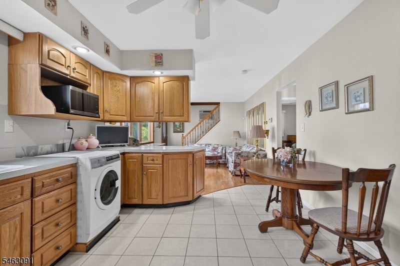Open-plan kitchen and dining area with wooden cabinets, tiled floor, and a round dining table.