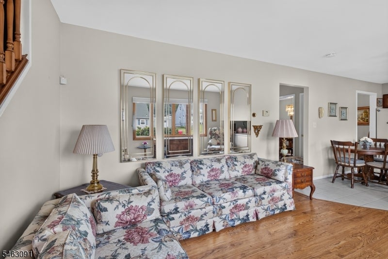 Living room with floral sofas, hardwood floors, and decorative mirrors above the couch.