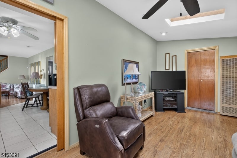 Living room with a leather recliner, television, wood floors, and a skylight.