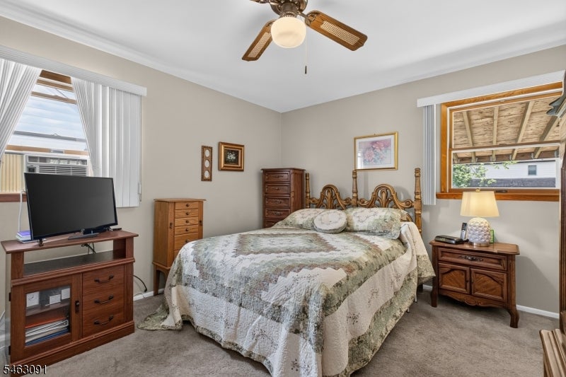 Bedroom with a carved wooden bed, ceiling fan, and television on a cabinet.