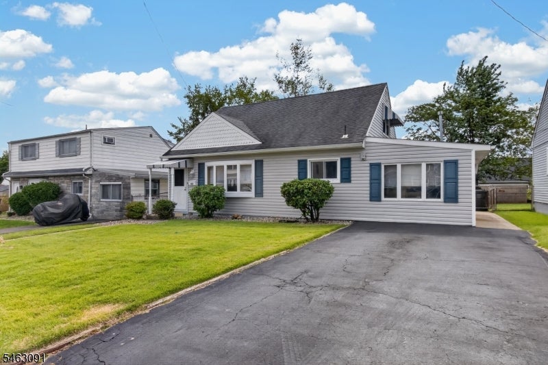 Gray-sided home with blue shutters, a broad driveway, and a green front lawn.