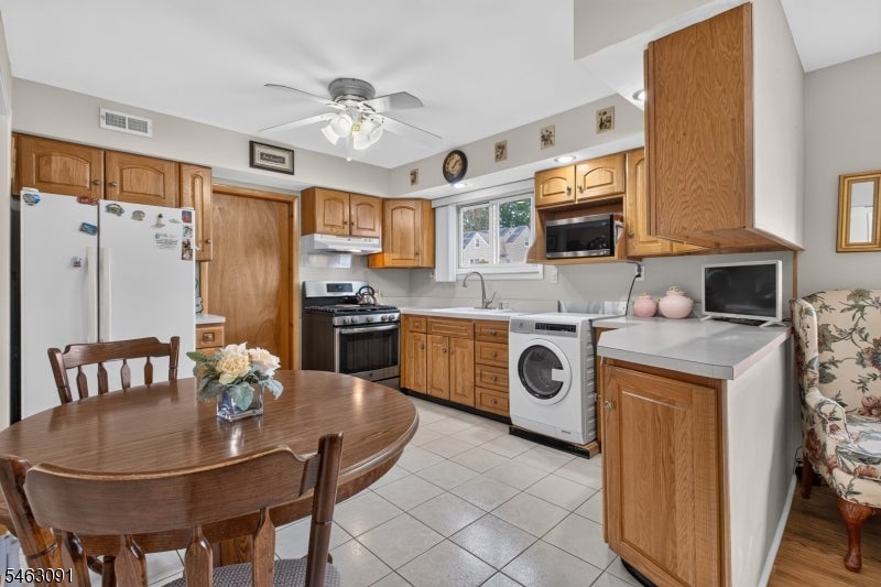 Kitchen with wood cabinets, a round dining table, and a front-loading washing machine.