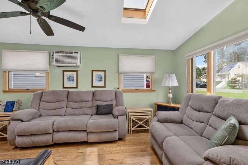 Living room with gray reclining sofas, a skylight, and large windows.