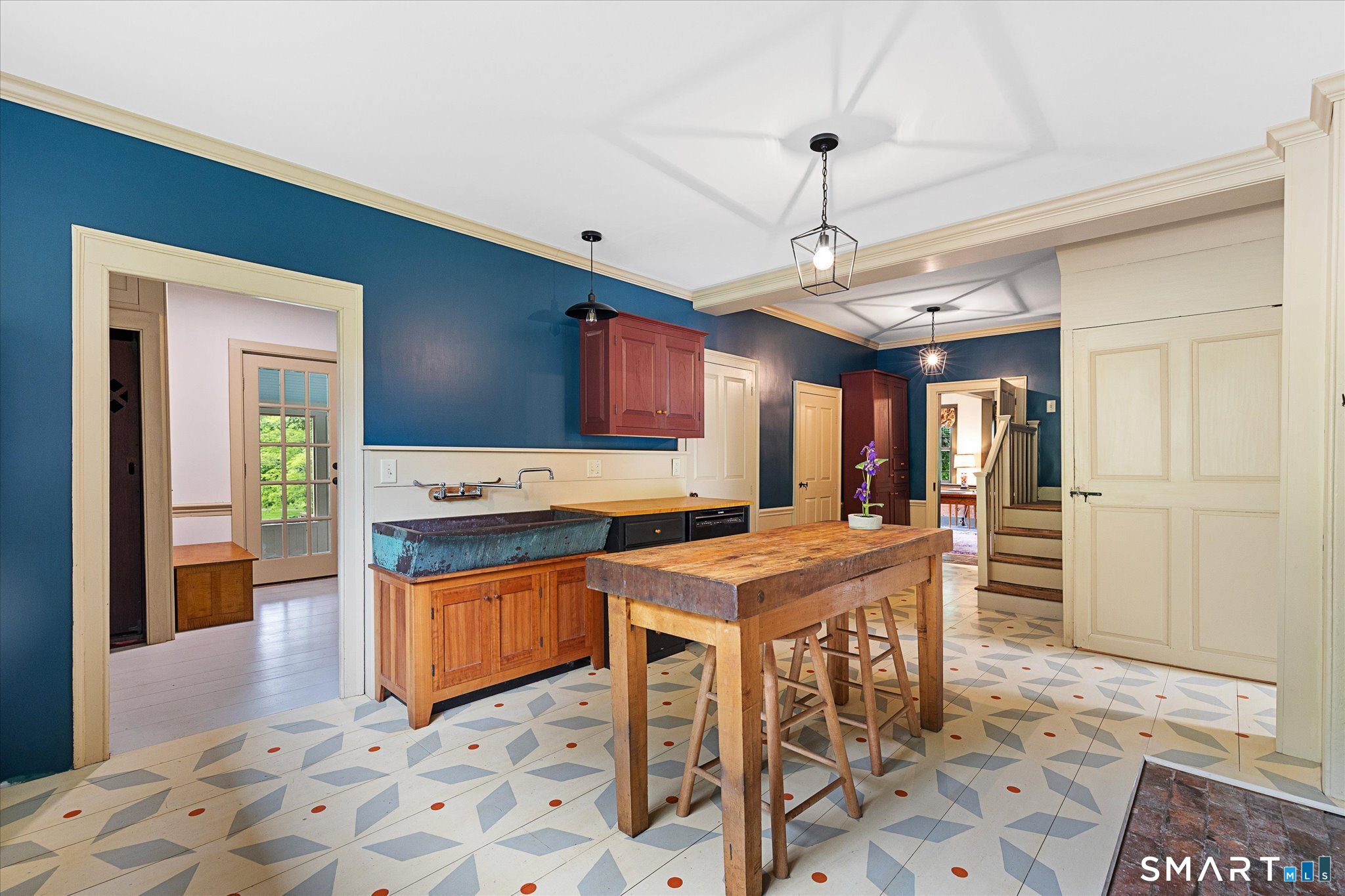 Kitchen with blue walls, red cabinets, a rustic wood island, and patterned tile flooring.