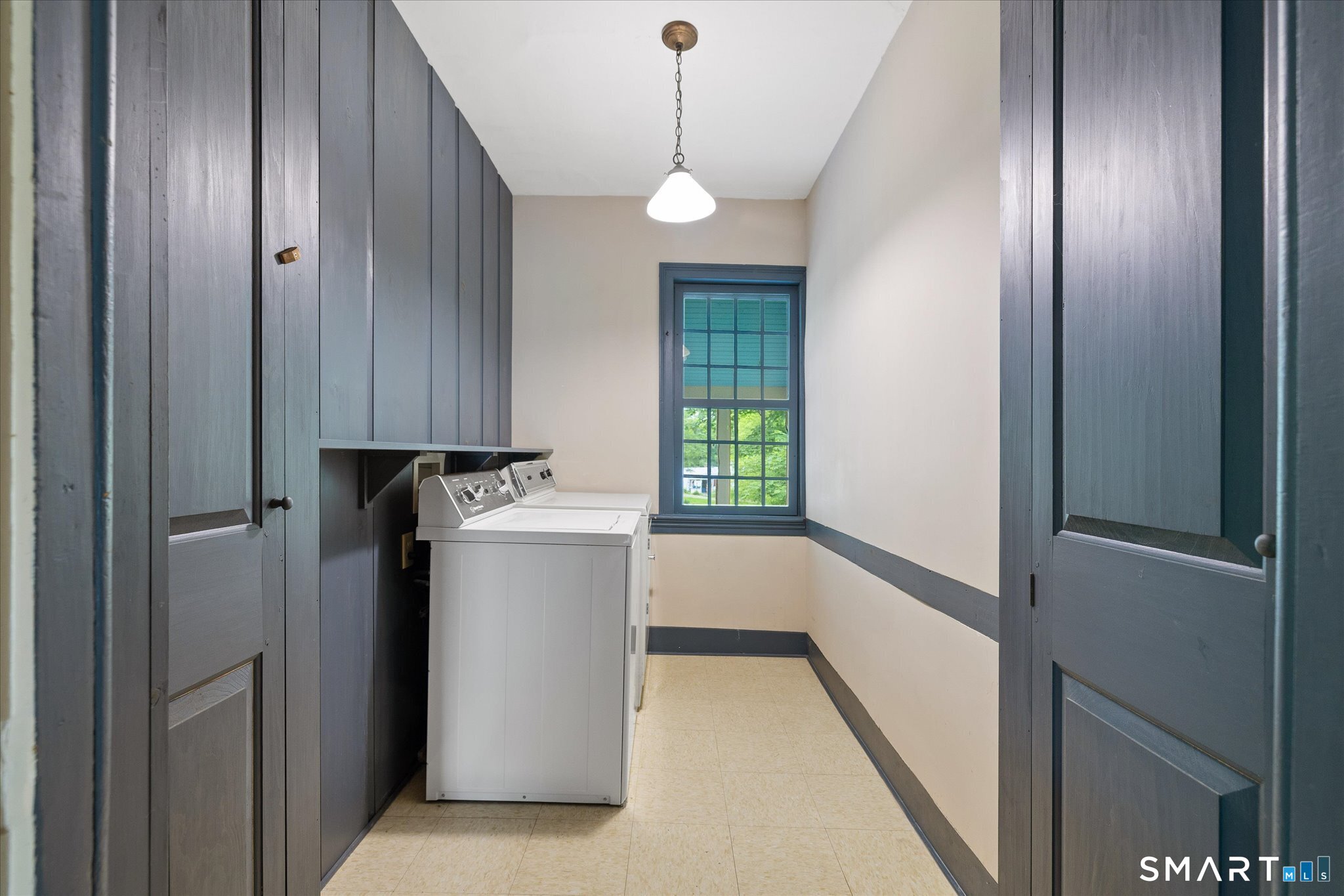 Laundry room with washer and dryer, dark built-in cabinets, and a window at the far end.