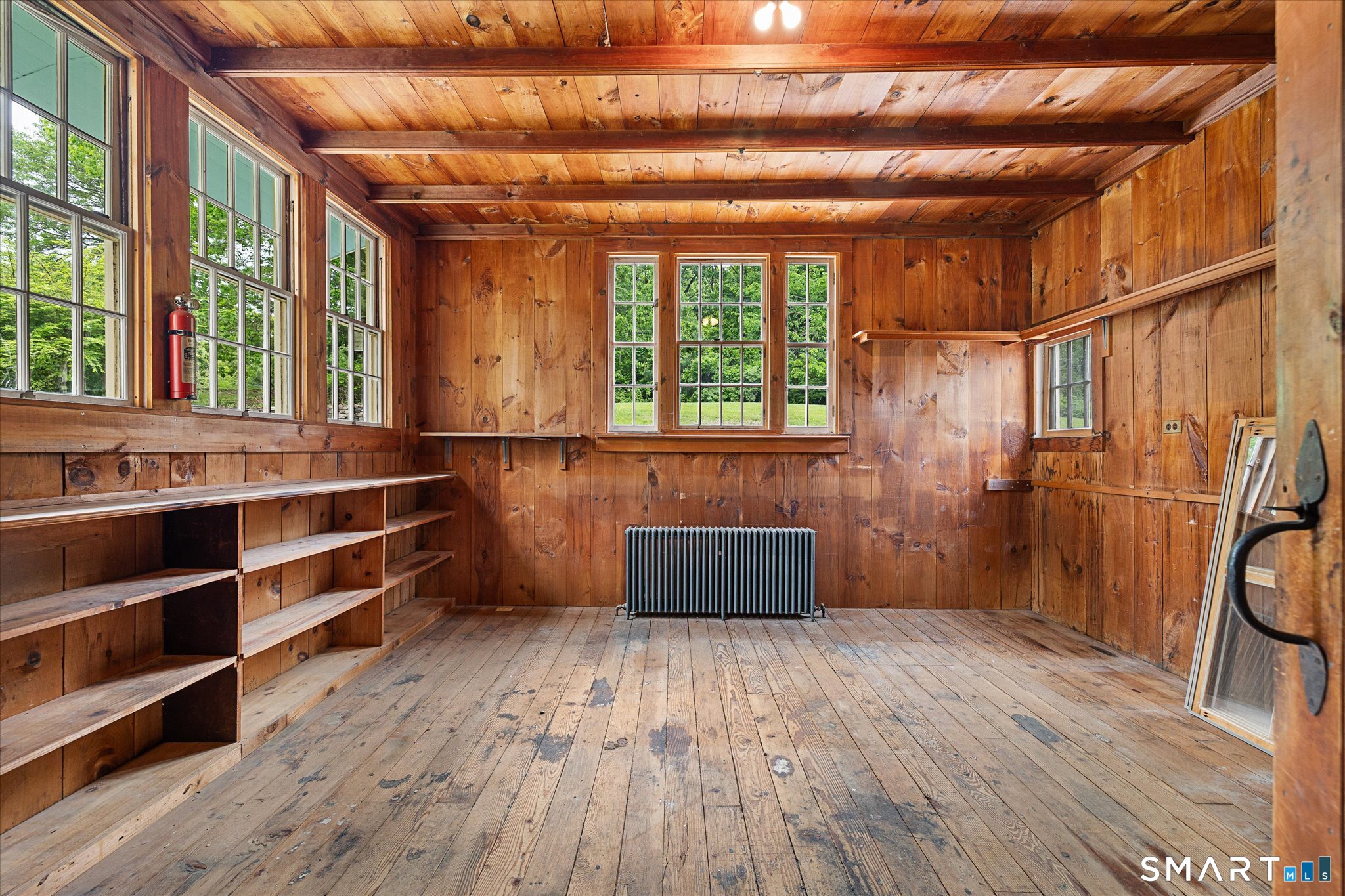 Wood-paneled room with built-in shelves, multiple windows, and a radiator.