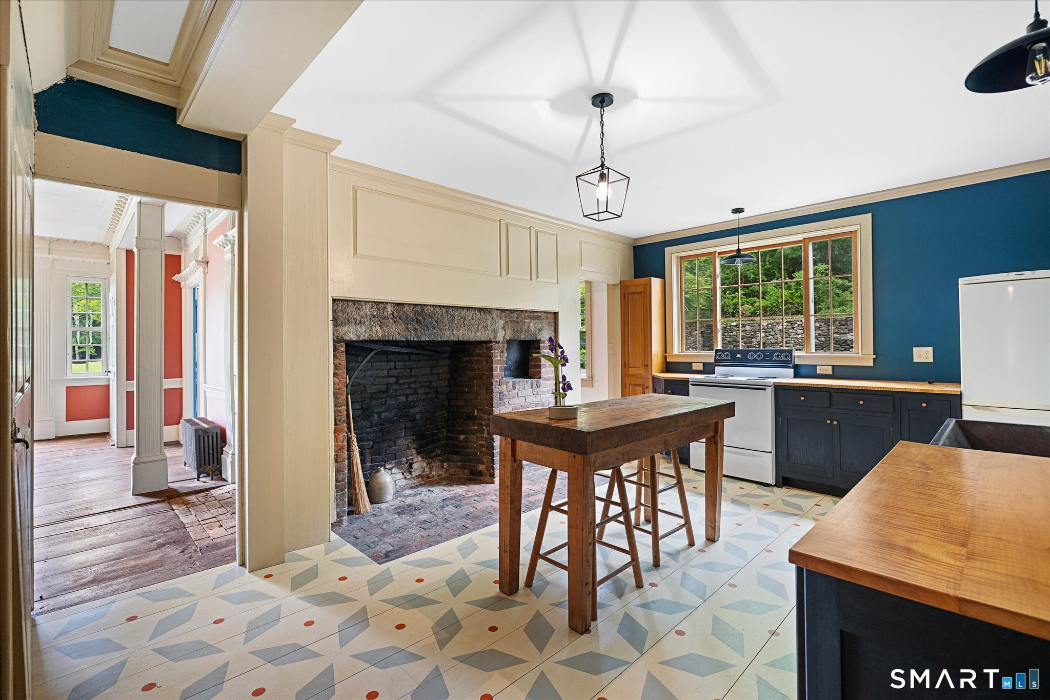Kitchen with a large brick fireplace, patterned tile floor, and rustic wooden island.