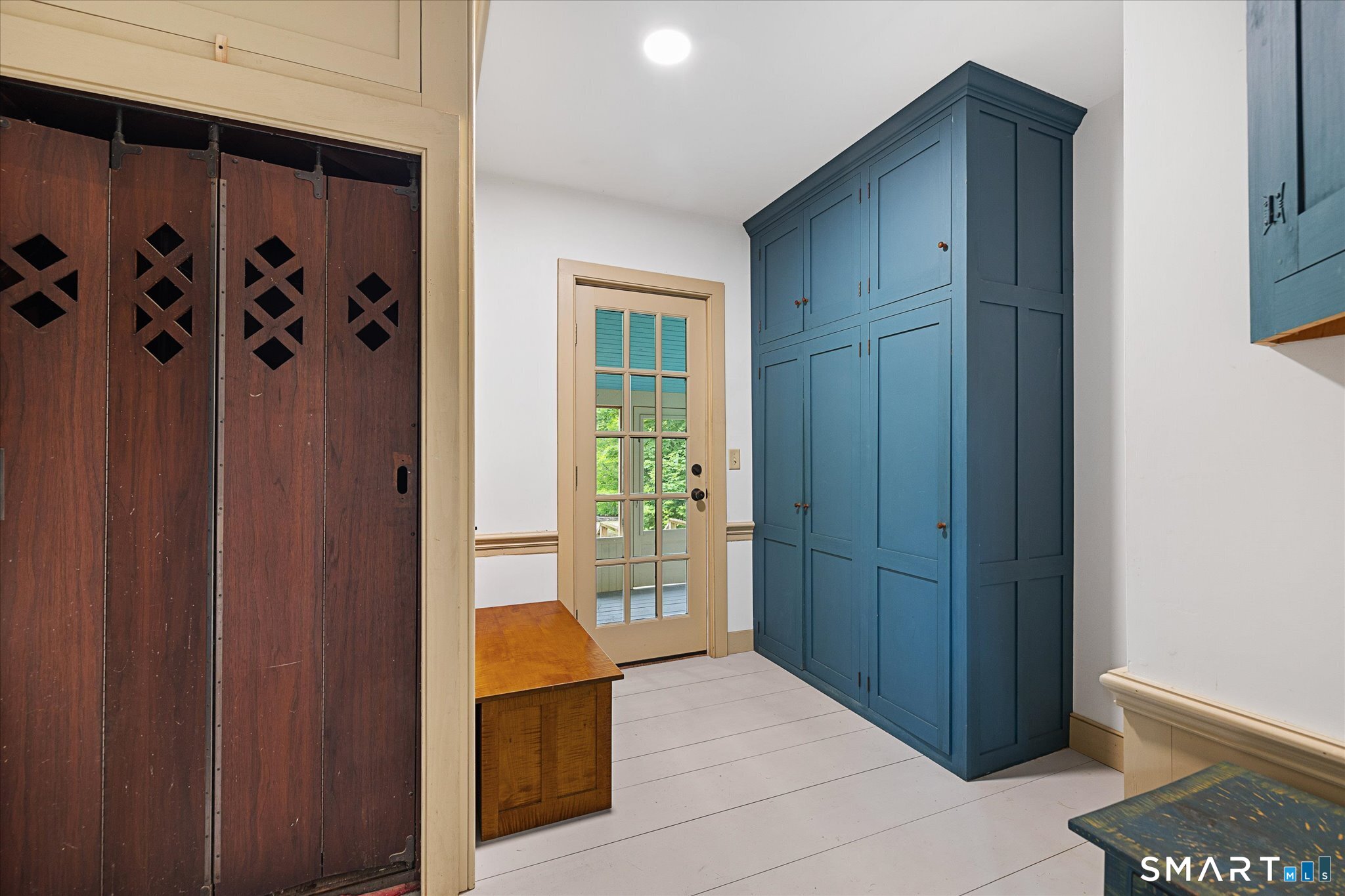 Entry hall with blue built-in cabinets, dark wooden sliding doors, and a glass-paneled exterior door.