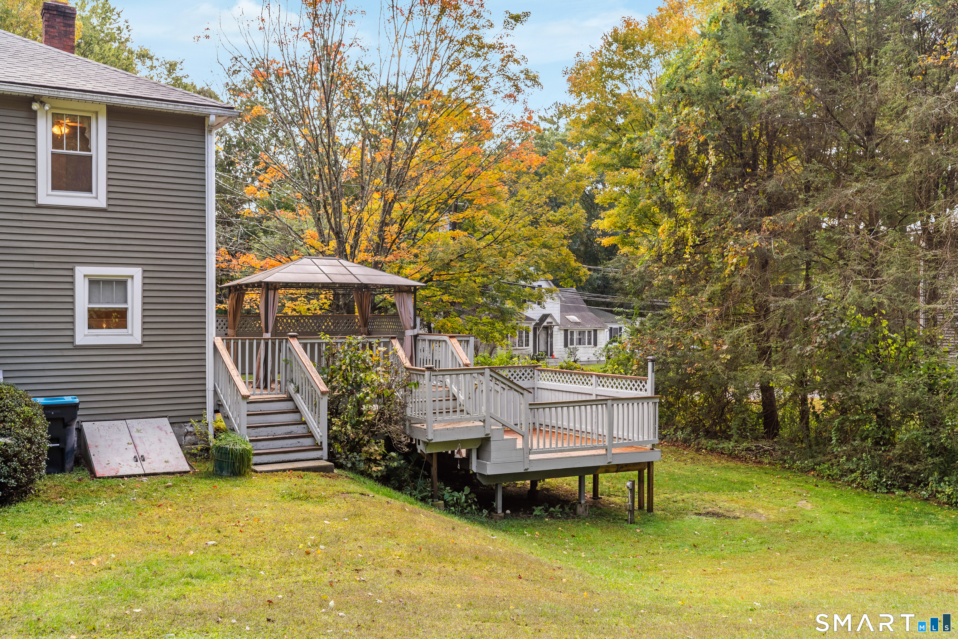 Raised deck with a covered gazebo beside the home, surrounded by autumn trees.