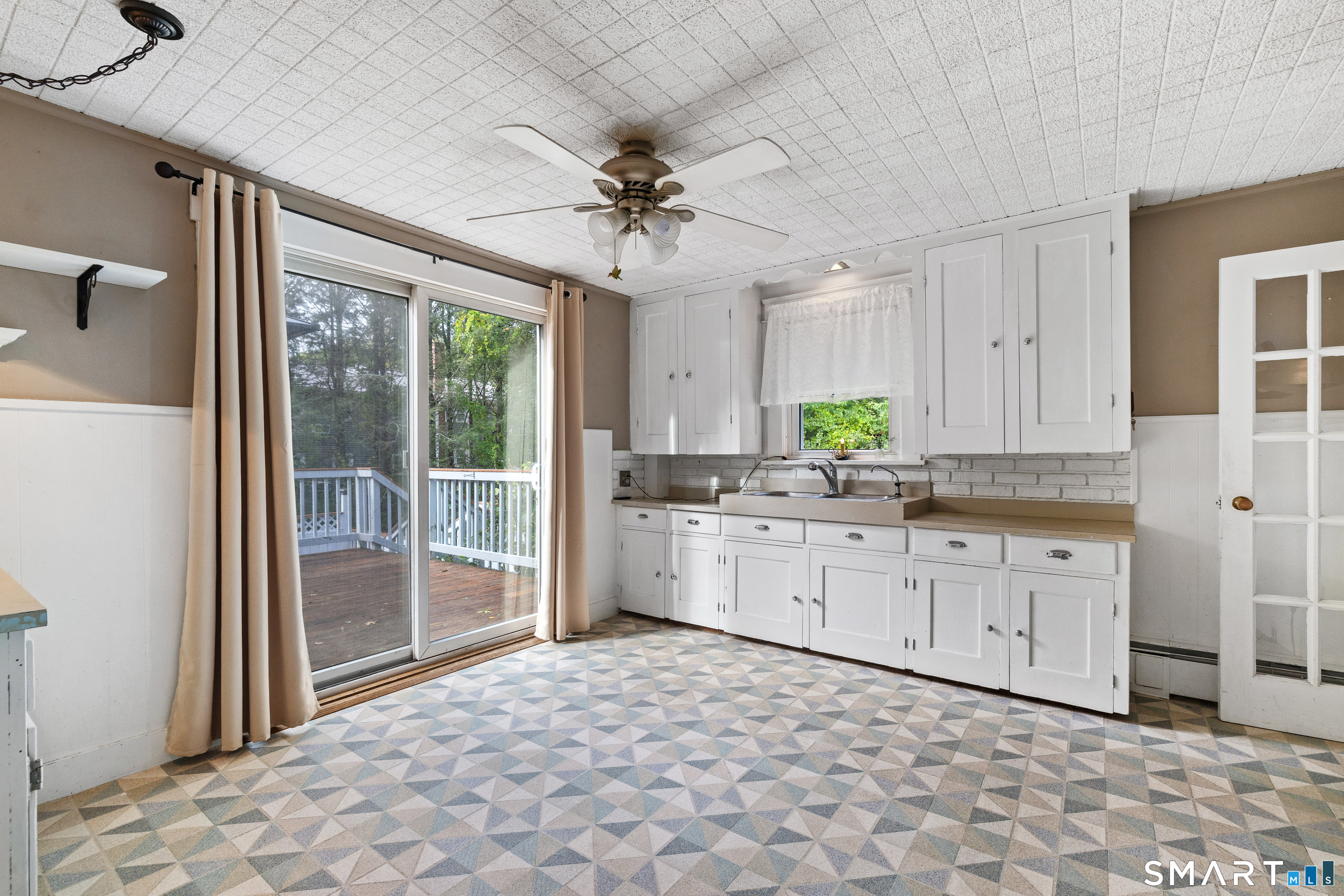 Kitchen with white cabinetry, geometric tile flooring, and sliding doors to a deck.