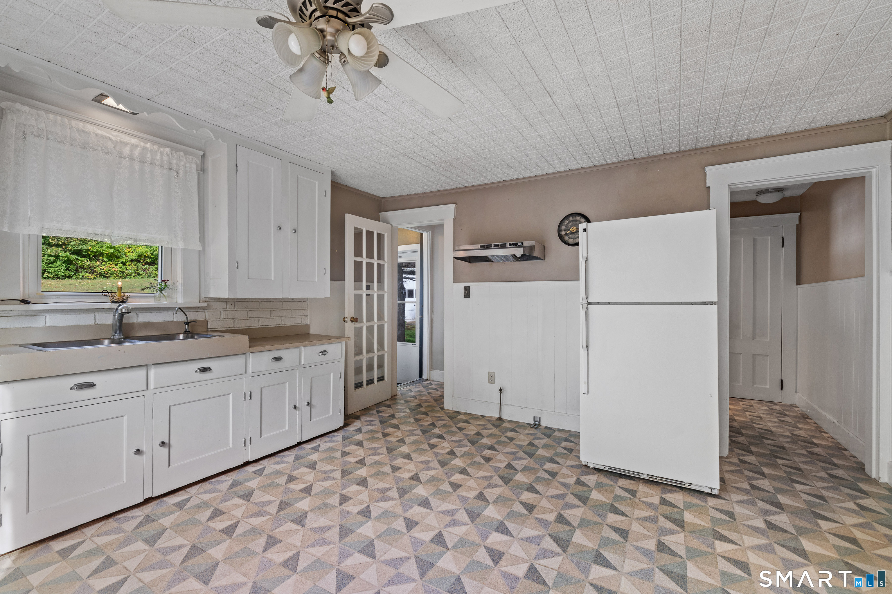 Kitchen with white cabinets, a large refrigerator, and colorful geometric tile flooring.