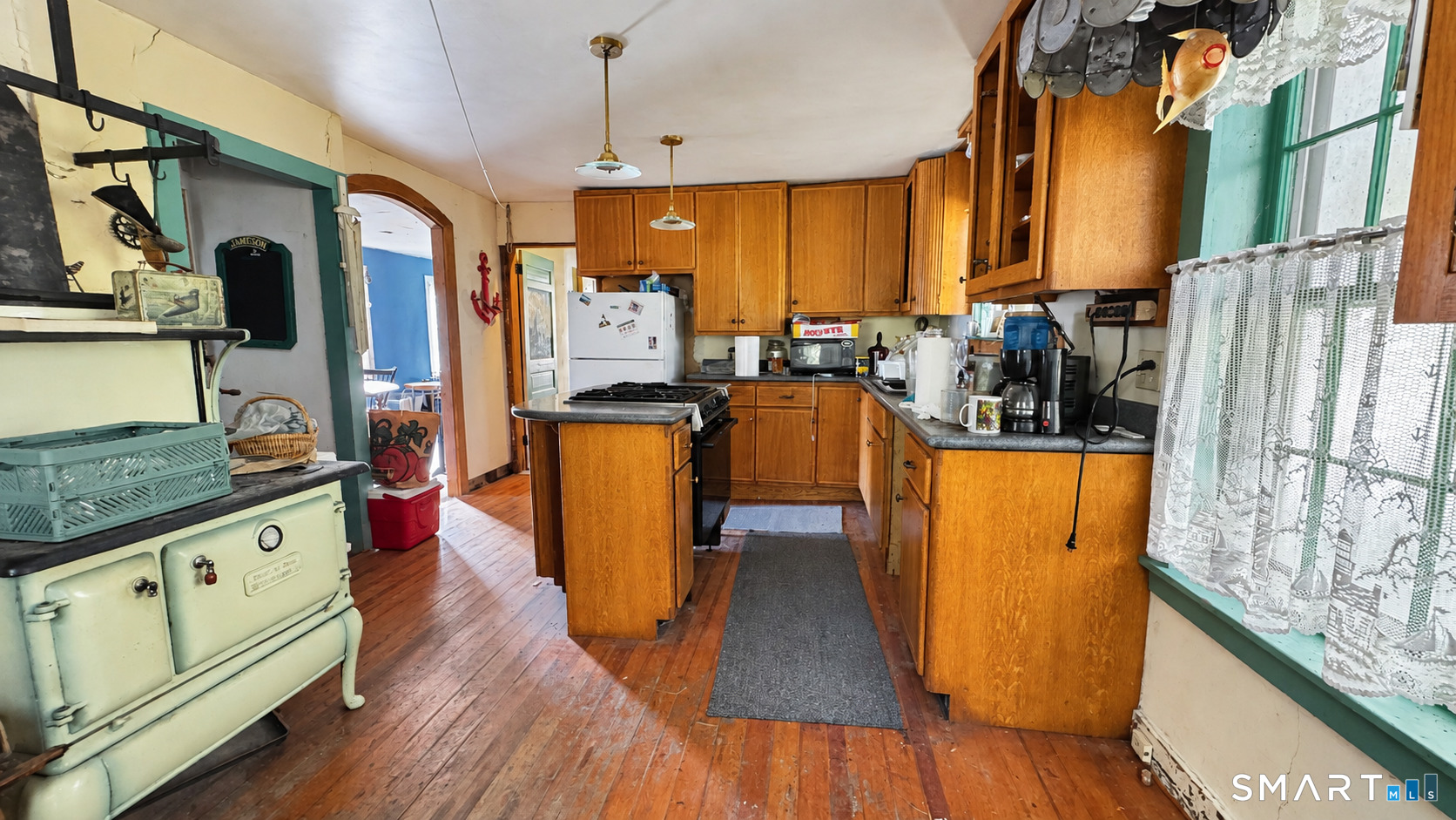 Kitchen with honey-colored cabinets, a central island, hardwood floors, and a vintage pale green cast-iron stove.
