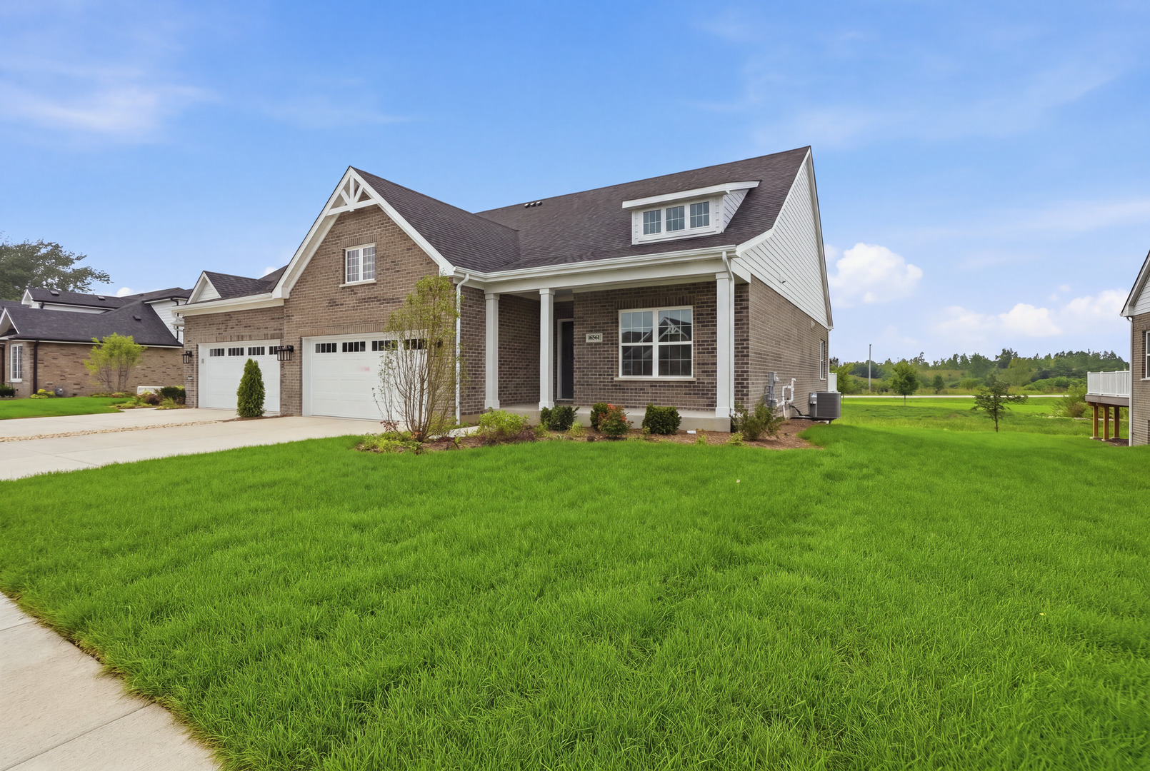 Brick-and-white two-story house with a double garage, covered entry, and broad green lawn.