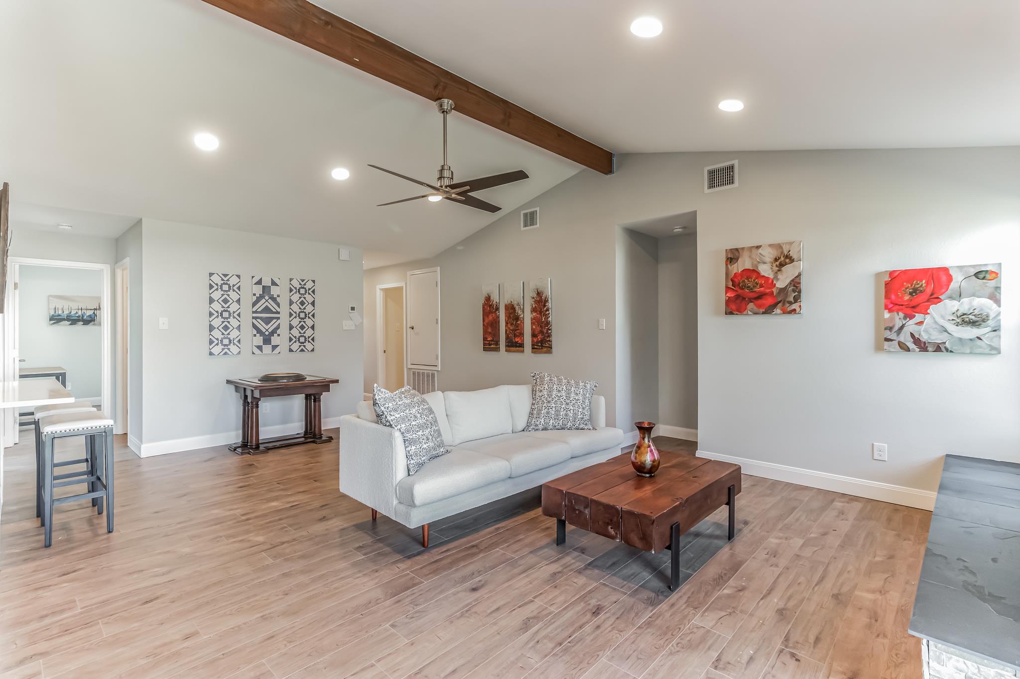 Living room with a white sofa, wood coffee table, vaulted ceiling, and exposed beam.