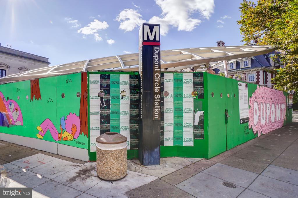 Dupont Circle Metro station entrance behind green, mural-covered construction fencing.