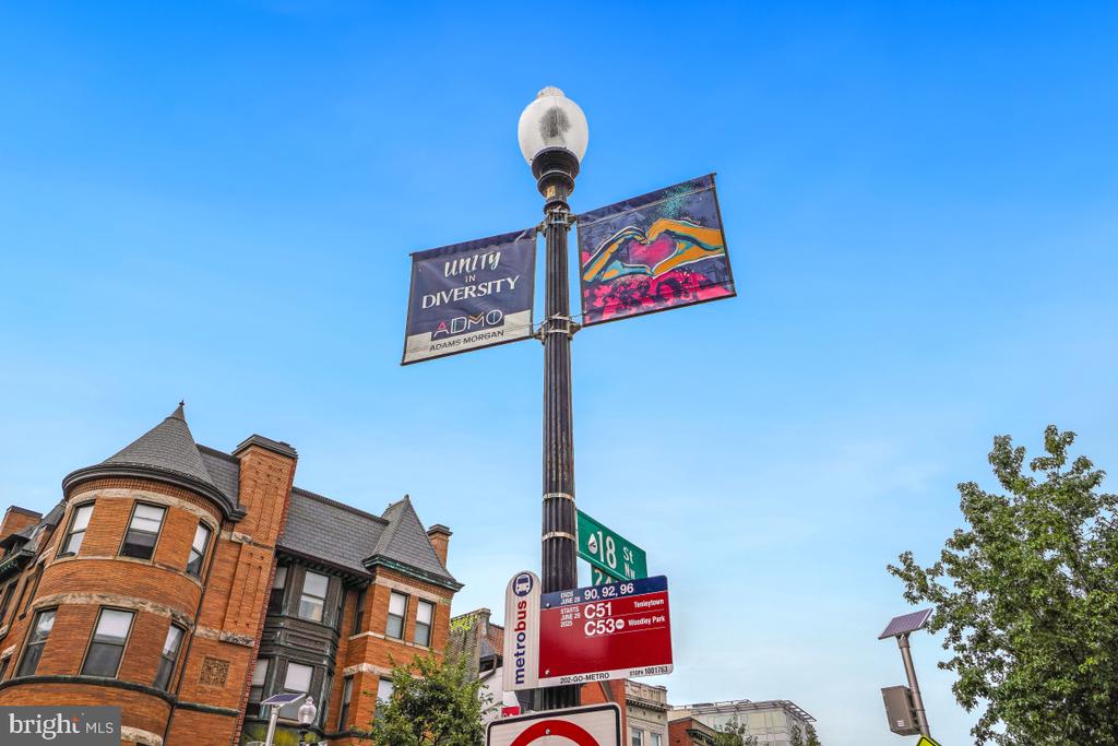 Street corner near 1954 Columbia Road NW, with historic brick buildings, Metrobus signs, and an 18th Street sign.