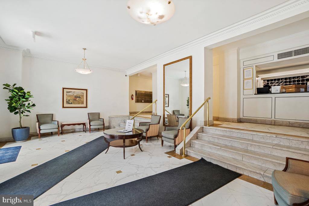 Condominium lobby with marble floors, seating, and a brass-railed staircase.