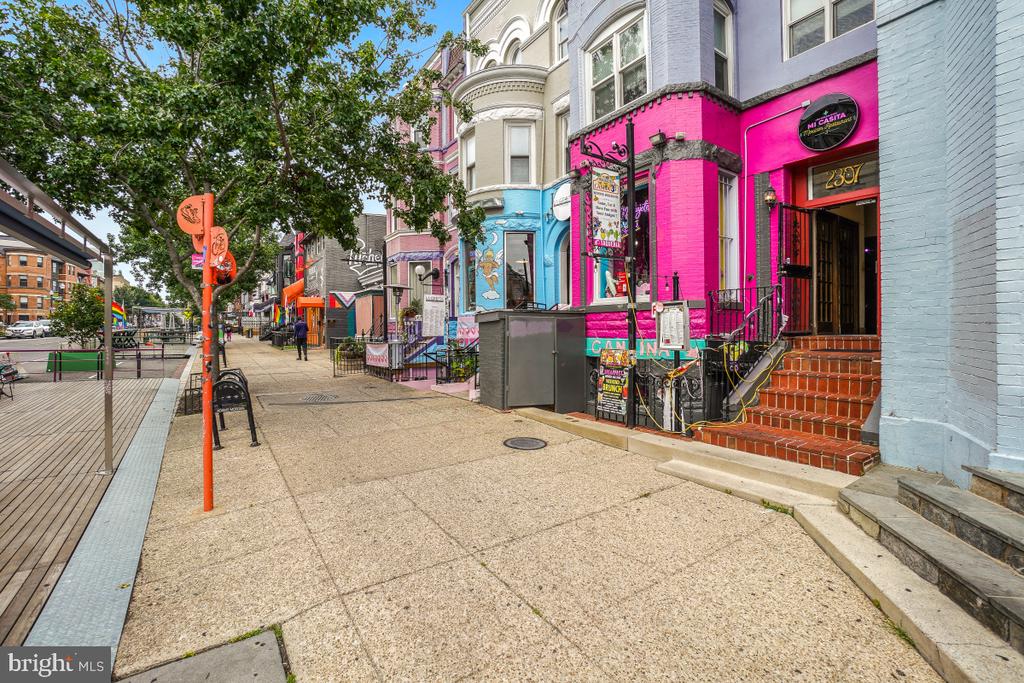 Colorful Columbia Road storefronts, including a bright pink restaurant beside a pedestrian plaza.