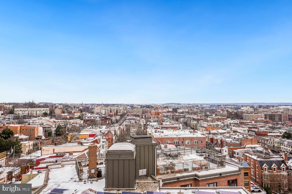Panoramic Washington, DC city view over snow-dusted rooftops beneath a clear blue sky.
