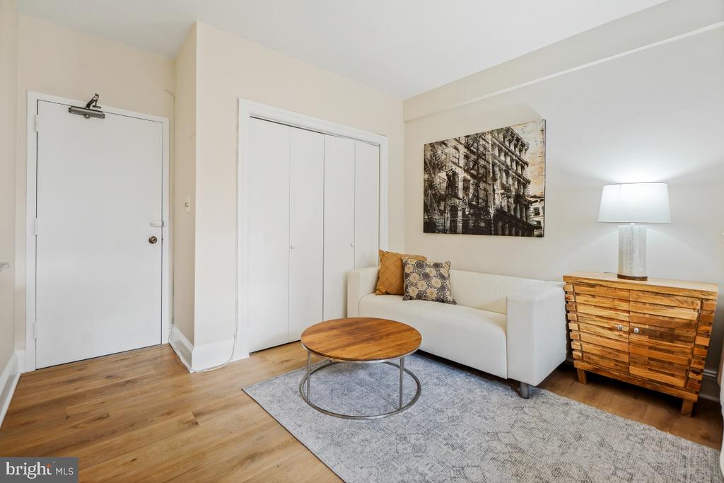 Staged living room with a white sofa, round wood coffee table, and hardwood floors.