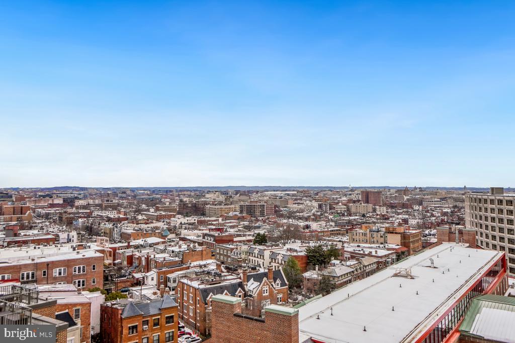 Panoramic view over snow-dusted Washington, DC rooftops beneath a clear blue sky.