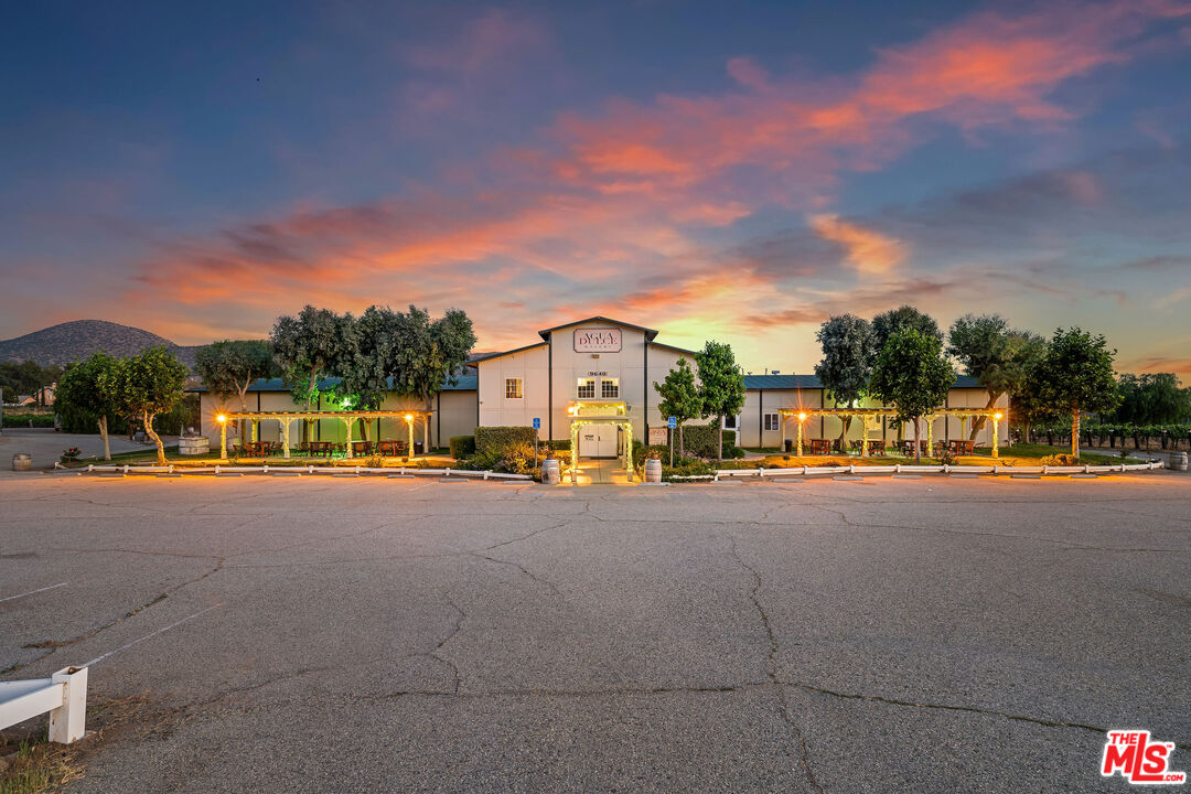 Commercial building with a central entrance and landscaped frontage beneath a colorful dusk sky.