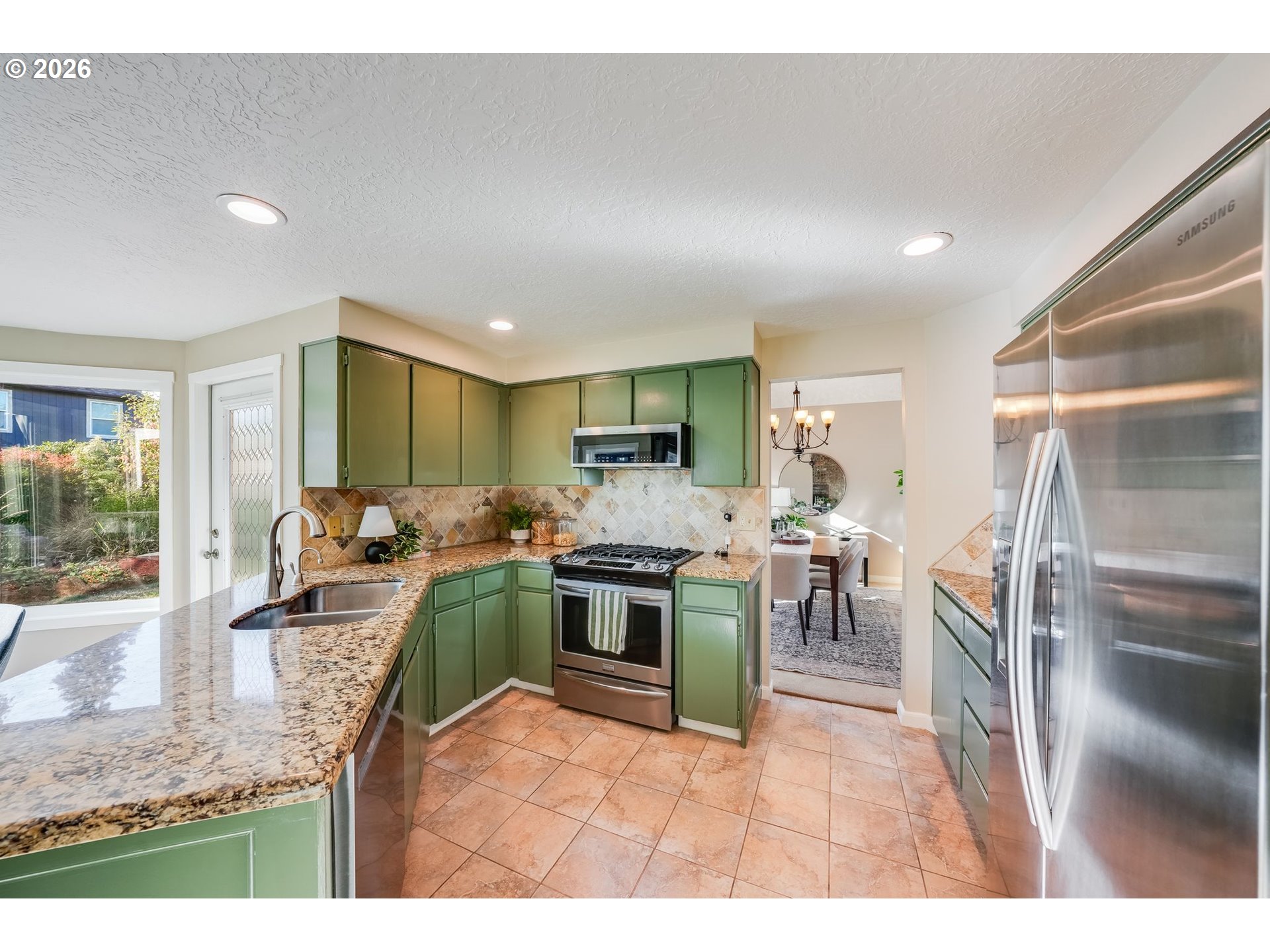 Kitchen with green cabinets, granite counters, and stainless steel appliances.